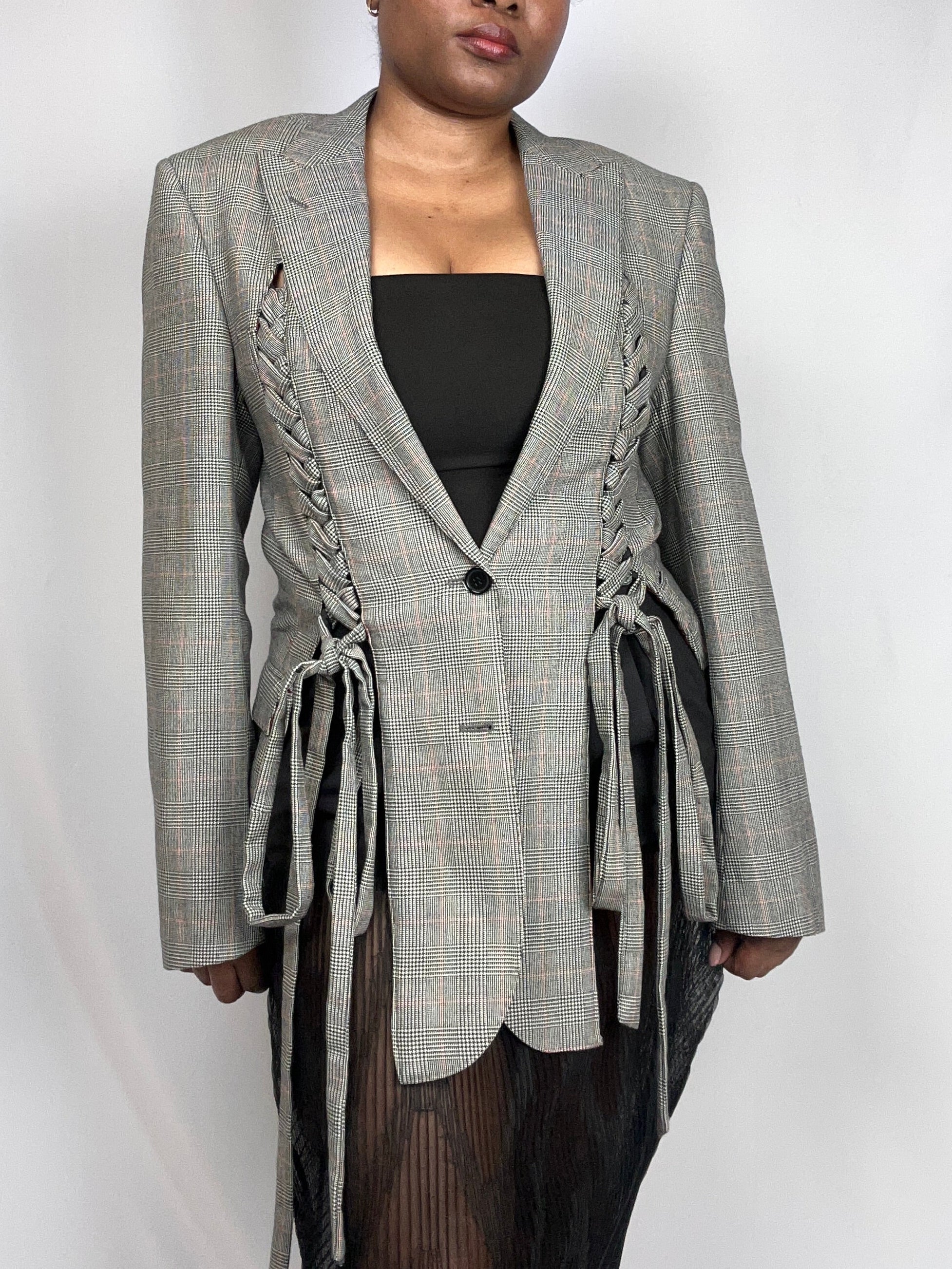 Person wearing a gray plaid blazer with lace-up front on a white background