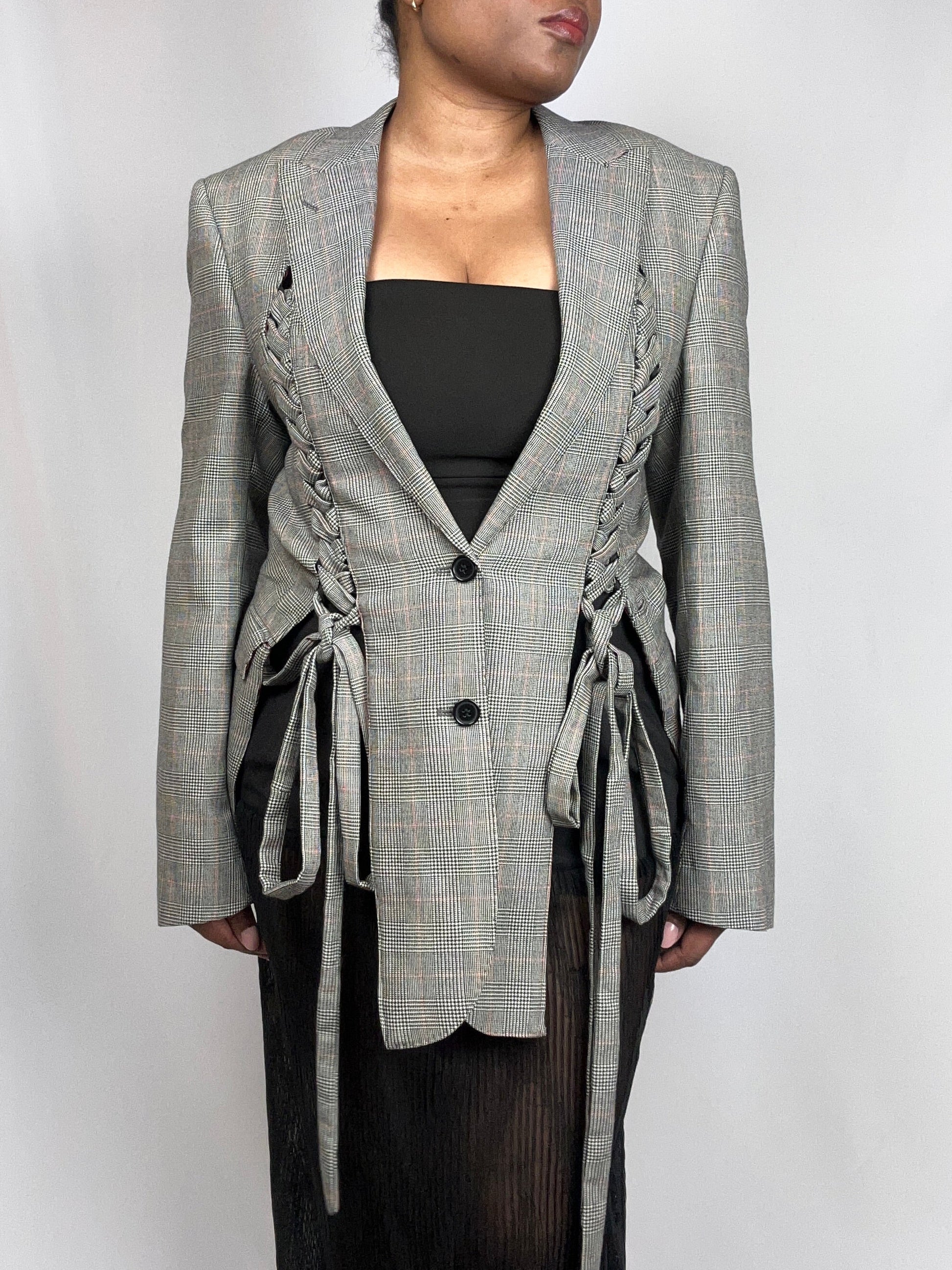 Person wearing a blazer with braided details on a white background